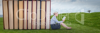 Business woman reading next to books outdoors