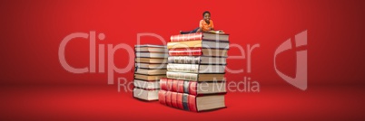 Boy reading on a pile of books with red background