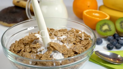 Pouring milk on cereals flakes for breakfast in slow motion