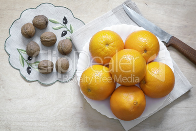 Oranges on a plate and walnuts.