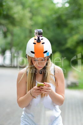 Young girl outdoors with action camera helmet and smart phone
