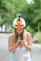 Young girl outdoors with action camera helmet and smart phone