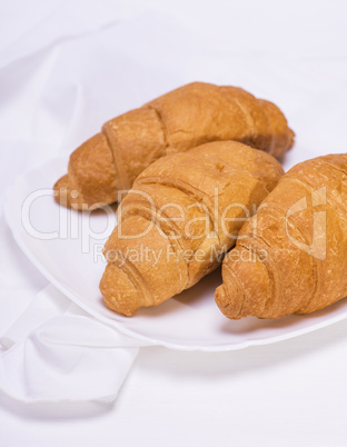 three baked croissants on a white plate