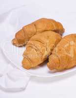 three baked croissants on a white plate