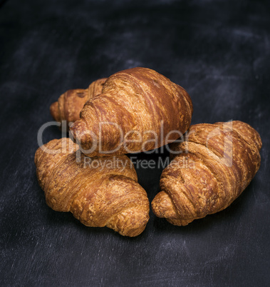 three baked croissants on a black background