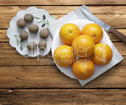 Oranges on a plate and walnuts.