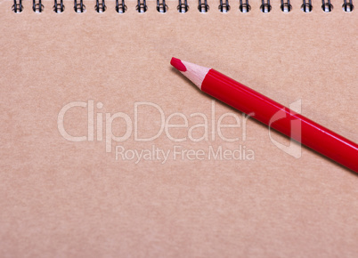 red wooden pencil on a brown sheet of paper