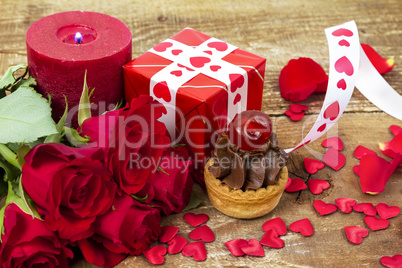 Cupcake with cherry in front of bouquet of red roses