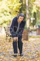 Senior woman having knee pain walking in park