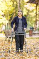 Woman with walker walking outdoors in autumn park