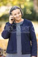 Positive senior woman talking on smartphone outdoors