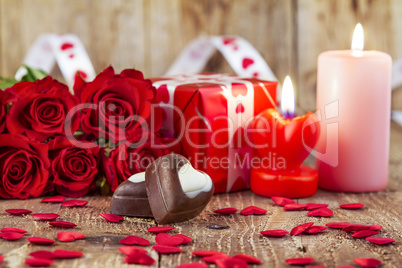 Chocolate pralines in front of bouquet of red roses