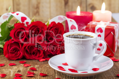 Cup with coffee in front of bouquet of red roses