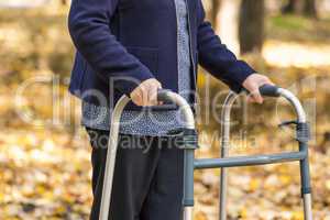 Senior woman legs walking with walker in autumn park