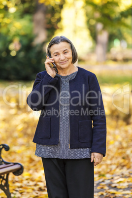 Senior woman talking on smartphone outdoors