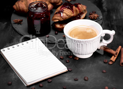 cup with black coffee and an empty paper notebook