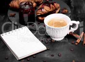 cup with black coffee and an empty paper notebook
