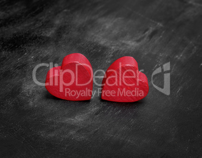 two red wooden hearts on a black background
