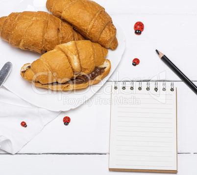 three baked croissants with chocolate and a paper notepad