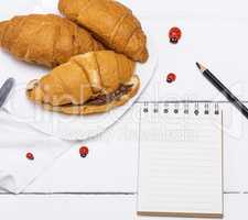 three baked croissants with chocolate and a paper notepad