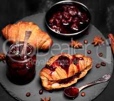 strawberry jam in a glass jar and baked croissant