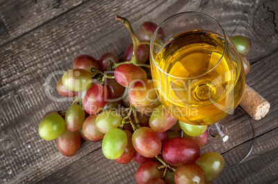 Glass of white wine with a cluster of grapes