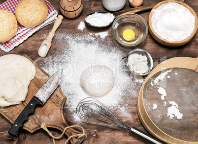 scattered wheat flour on the table, next to raw yeast dough
