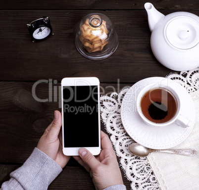 two female hands holding a white smartphone with an empty black