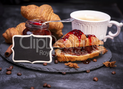 croissants with raspberry jam and black empty wooden plaque
