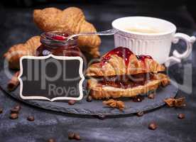 croissants with raspberry jam and black empty wooden plaque