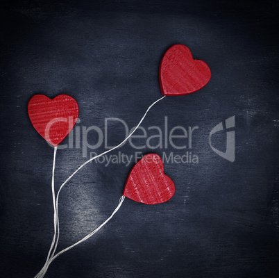 three red wooden hearts on a white string