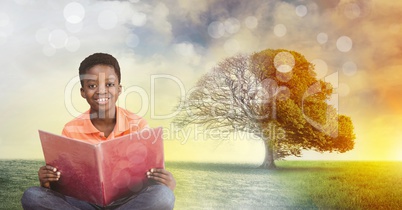 Boy holding book with magical surreal seasonal tree imagination