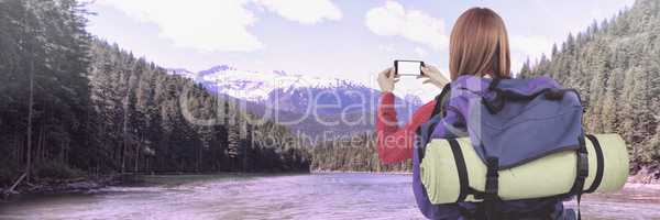 Travelling woman with bag and phone in front of landscape