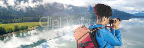 Travelling woman with bag and camera in front of landscape