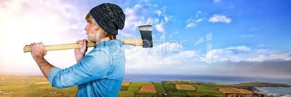 Man holding axe in front of green landscape