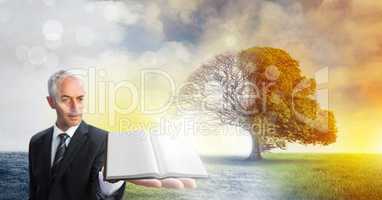 Man holding book with magical surreal seasonal tree imagination