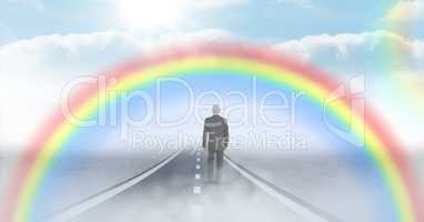 Businessman walking on road with rainbow