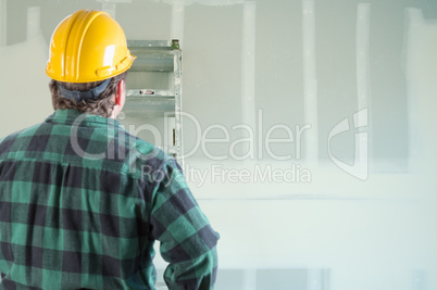 Contractor in Hard Hat Looking at Drywall.