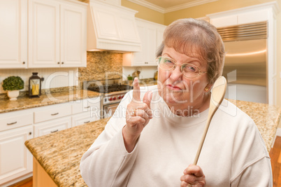 Senior Adult Woman Scolding with The Wooden Spoon Inside Kitchen