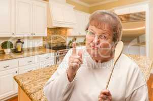 Senior Adult Woman Scolding with The Wooden Spoon Inside Kitchen