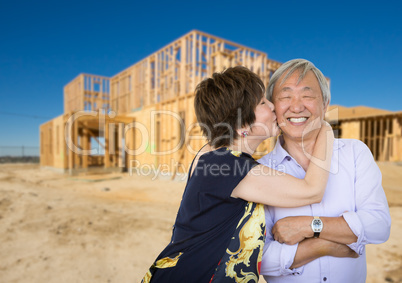 Chinese Senior Adult Couple Kissing In Front Of New House Framin