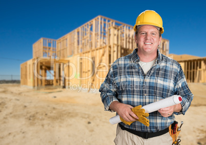 Contractor with Plans and Hard Hat In Front of New House Framing