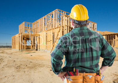 Contractor with Hard Hat Looking At New House Framing at Constru