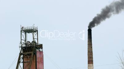 Industrial mine billowing smoke into blue skies