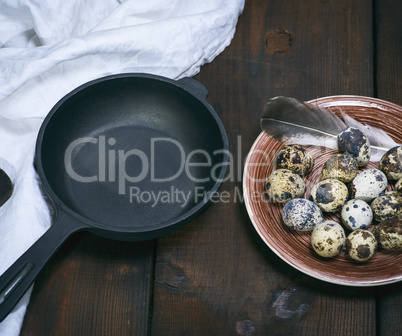 empty round cast-iron frying pan and raw quail eggs in a plate