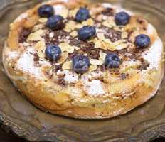 a round baked pie with apples and blueberries