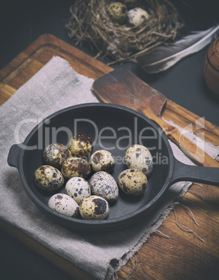 quail eggs in the shell lie in a black cast-iron frying pan