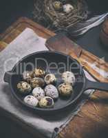 quail eggs in the shell lie in a black cast-iron frying pan