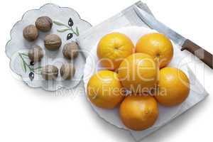 Oranges in the bowl and walnuts on a white background.