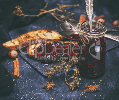 raspberry jam in a glass jar with an iron spoon